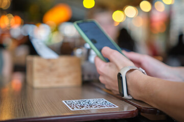 Closeup of guest hand ordering meal in restaurant while scanning qr code with mobile phone for online menu