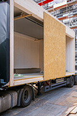 Wall Mural - Prefabricated wooden building module on a truck, ready to beeing set into the building by a crane.