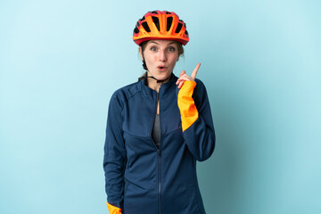 Wall Mural - Young cyclist woman isolated on blue background intending to realizes the solution while lifting a finger up