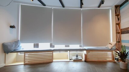 Poster - Video of motorized roller shades in the interior. Automatic roller blinds beige color open up on big glass windows. Remote Control Shades are above the windowsill with pillows. Summer. 