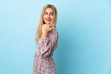 Wall Mural - Young Uruguayan blonde woman over isolated blue background pointing to the side to present a product