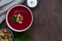 Red Beet Soup With Bread.vegetable Soup With Greens. Bowl Of Beetroot Cream Soup With White Cream And Croutons On A Brown Wooden Background. Healthy Dietary Lunch. Flat Lay, Top View. Copy Space