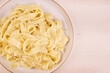 Fettuccine Alfredo. Fettuccine with cheese and butter sauce, portion in a plate, top view, copy space