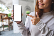 Mockup Image Of A Young Woman Holding And Pointing Finger At A Mobile Phone With Blank White Screen