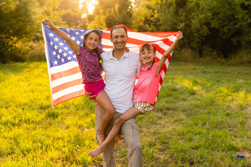 Happy family in field with USA, american flag on back.