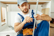 © Kostiantyn - Busy male worker in overalls holding a kitchen drawer particle while assembling kitchen furniture in apartment