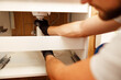© Kostiantyn - Closeup of hands of professional plumber fixing sink, changing water pipe in apartment