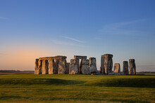 Stonehenge, A Prehistoric Monument During Early Morning. Pink Orange Glow And Blue Sky