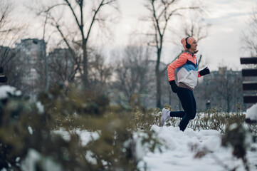 Wall Mural - Woman running in the park on a cold winter day.