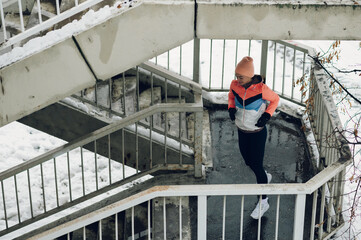 Wall Mural - Young woman running on the stairs in the winter.