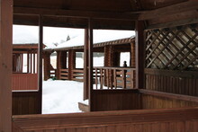 Brown Wooden Gazebo With Snow On The Roof On Snowy Background 