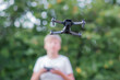 A teenager with a drone remote control. The child controls a toy drone in the yard of the house.