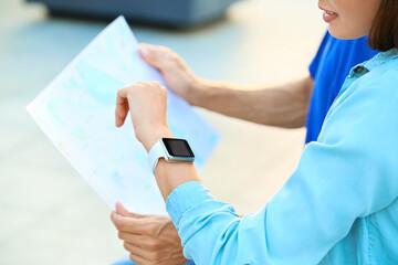 Wall Mural - Couple of young tourists with map and smartwatch outdoors