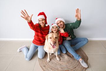 Sticker - Happy family in Santa hats and cute Labrador dog near light wall