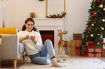 Poster - Beautiful young woman with cup of hot chocolate at home on Christmas eve