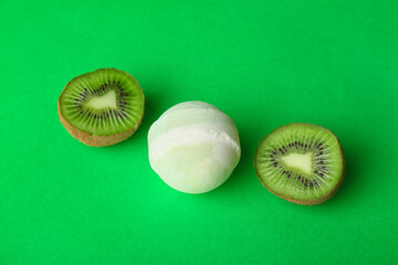 Bath bomb and kiwi on green background