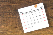 May 2022 Calendar And Wooden Push Pin On Wooden Background.