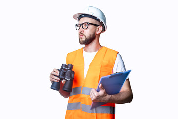 Young man in building clothes, with binoculars, with a clipboard on a light background.