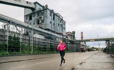 Sticker - Sportswoman running alone in an industrial zone