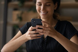 Fototapeta  - Close up cropped image young woman holding cellphone in hands, typing message in social network, reading email with pleasant news, playing mobile game, shopping in internet store or web surfing.