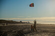 Father and son flying kite together on the beach in winter sunshine