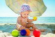The baby is playing on the beach. Child at sea. Toys for sand and water. Sun protection for young children.