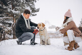 Fototapeta Las - Family walking in winter park with their dog