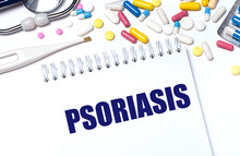 On A Light Background, Multi-colored Pills, A Stethoscope, An Electronic Thermometer And A Notebook With The Text PSORIASIS. Medical Concept.