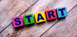 © Елена Дигилевич - On a dark wooden background, multicolored bright wooden cubes with the text START
