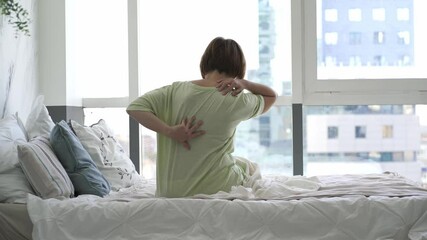 Wall Mural - Back pain, woman with backache in the bedroom, health problems concept
