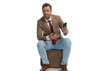 Wall Mural - seated businessman pointing at his phone