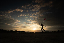 Silhouette Of Children Flying A Kite On Sunset
