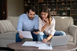 © fizkes - Focused husband and wife sit at table at home pay utilities online, young couple make internet payment use e-bank app, calculates expenses, family budget and finances management, monthly costs concept