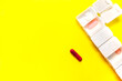 © Kemedo - White weekly pillbox with different tablets of colors isolate on yellow background with big copy space left.