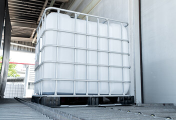 Low view with shade of a large white chemical tank on track roller inside of the factory.