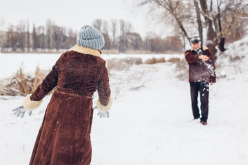 Wall Mural - Senior family couple playing snowballs outdoors during snowy winter weather. Elderly people having fun. Valentine's day