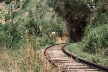 Rustic Railroad Leading Into Dark Tunnel Surrounded By Grass