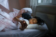 © DimaBerlin - Social media jealousy. Young depressed woman addicted to mobile phone lying in bed at home, scrolling social media, feeling envious of lives of others, reading what people posting and sharing online