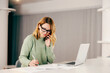 © dusanpetkovic1 - A busy woman talking on the phone and finishing paperwork while working from home.