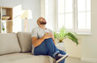 © Studio Romantic - Millennial man with rheumatism, arthritis or osteoarthritis experiences severe pain in knee joint. Unhappy suffering man grimaces from terrible knee pain while sitting on sofa at home. Health concept.