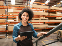 Female Employee Climbing Stairs And Looking At Camera At Warehouse