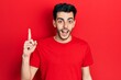 © Krakenimages.com - Young hispanic man wearing casual clothes pointing finger up with successful idea. exited and happy. number one.