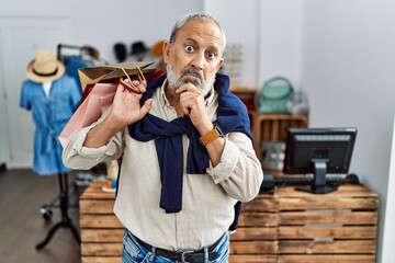 Poster - Handsome senior man holding shopping bags at boutique shop thinking worried about a question, concerned and nervous with hand on chin