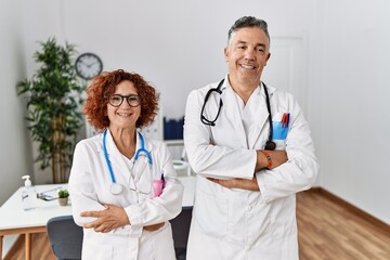 Poster - Two middle age doctors at medical clinic happy face smiling with crossed arms looking at the camera. positive person.