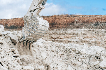 Close-up view of excavator large bucket on construction site or quarry. Mining heavy machinery details. Earthmoving, excavations, digging on soils.