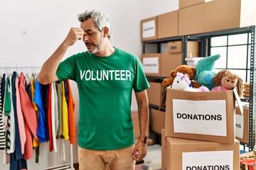 Sticker - Middle age hispanic man wearing volunteer t shirt at donations stand tired rubbing nose and eyes feeling fatigue and headache. stress and frustration concept.