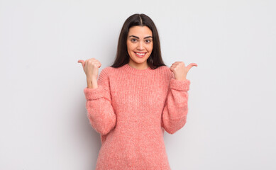 pretty young woman smiling joyfully and looking happy, feeling carefree and positive with both thumbs up