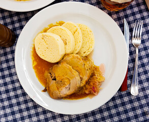 Wall Mural - Top view of traditional old Bohemian dumplings served with sauerkraut and baked pork on white plate. Dish of Czech cuisine