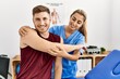© Krakenimages.com - Young hispanic physioterapist woman make arm rehab treatment to man at the clinic.