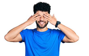 Sticker - Young arab man with beard wearing casual blue t shirt covering eyes with hands smiling cheerful and funny. blind concept.